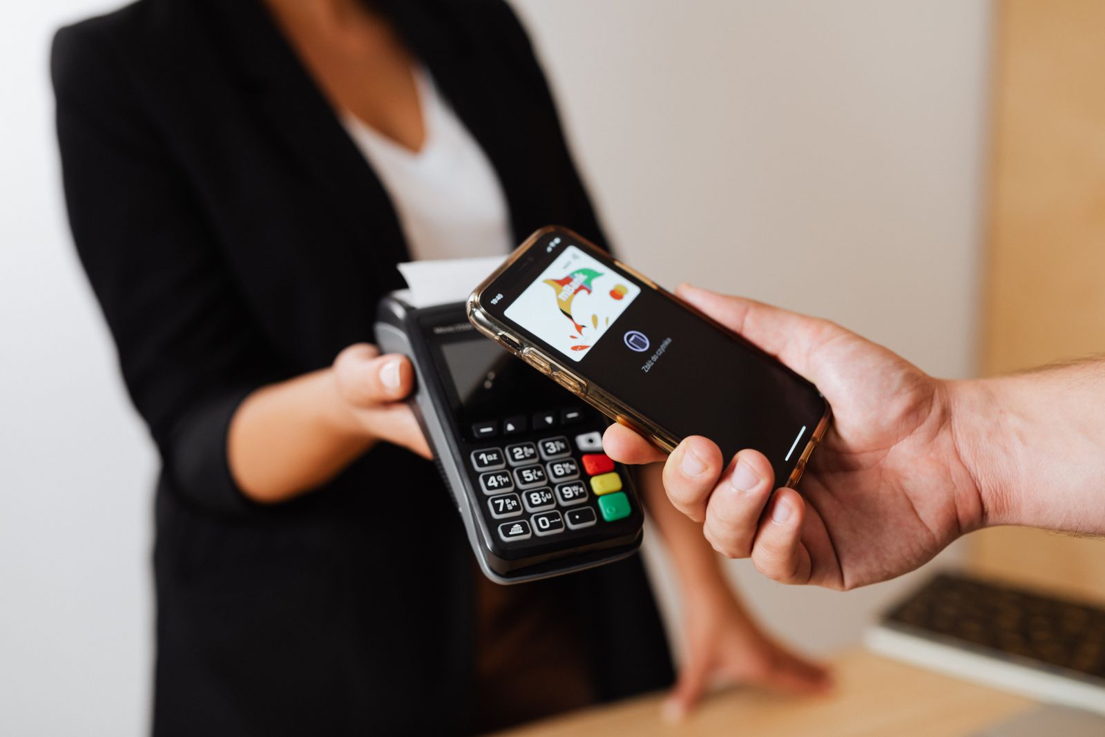 Klient zbliżający smartfon do terminala płatniczego