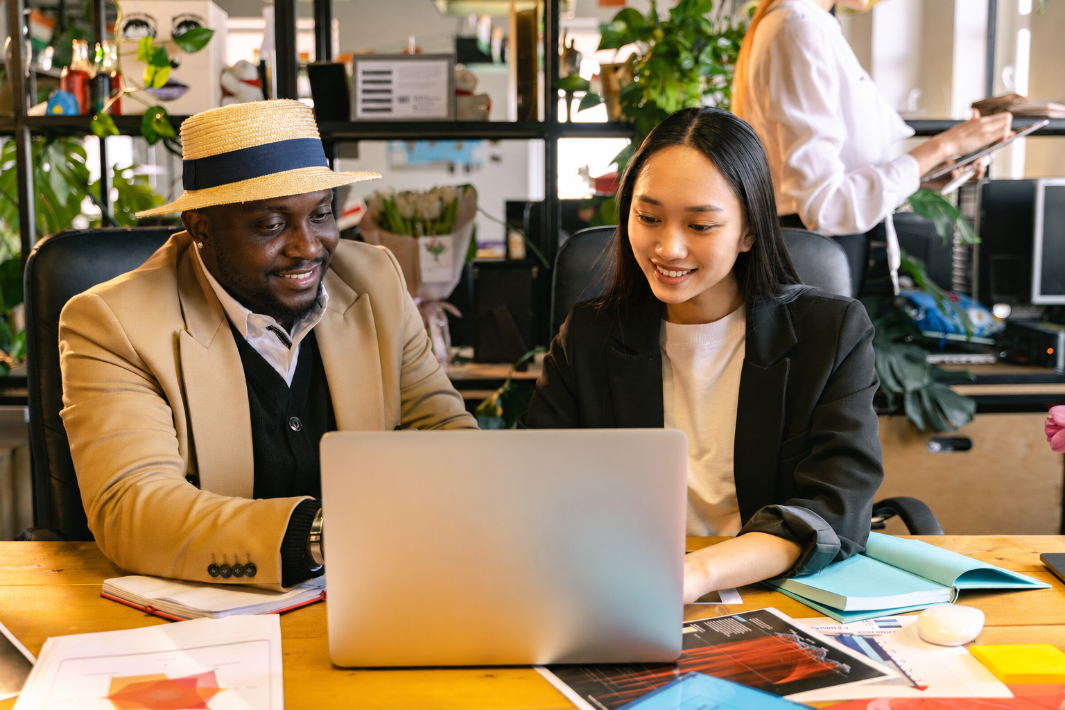 Duas pessoas sorrindo enquanto analisam um notebook e anotações